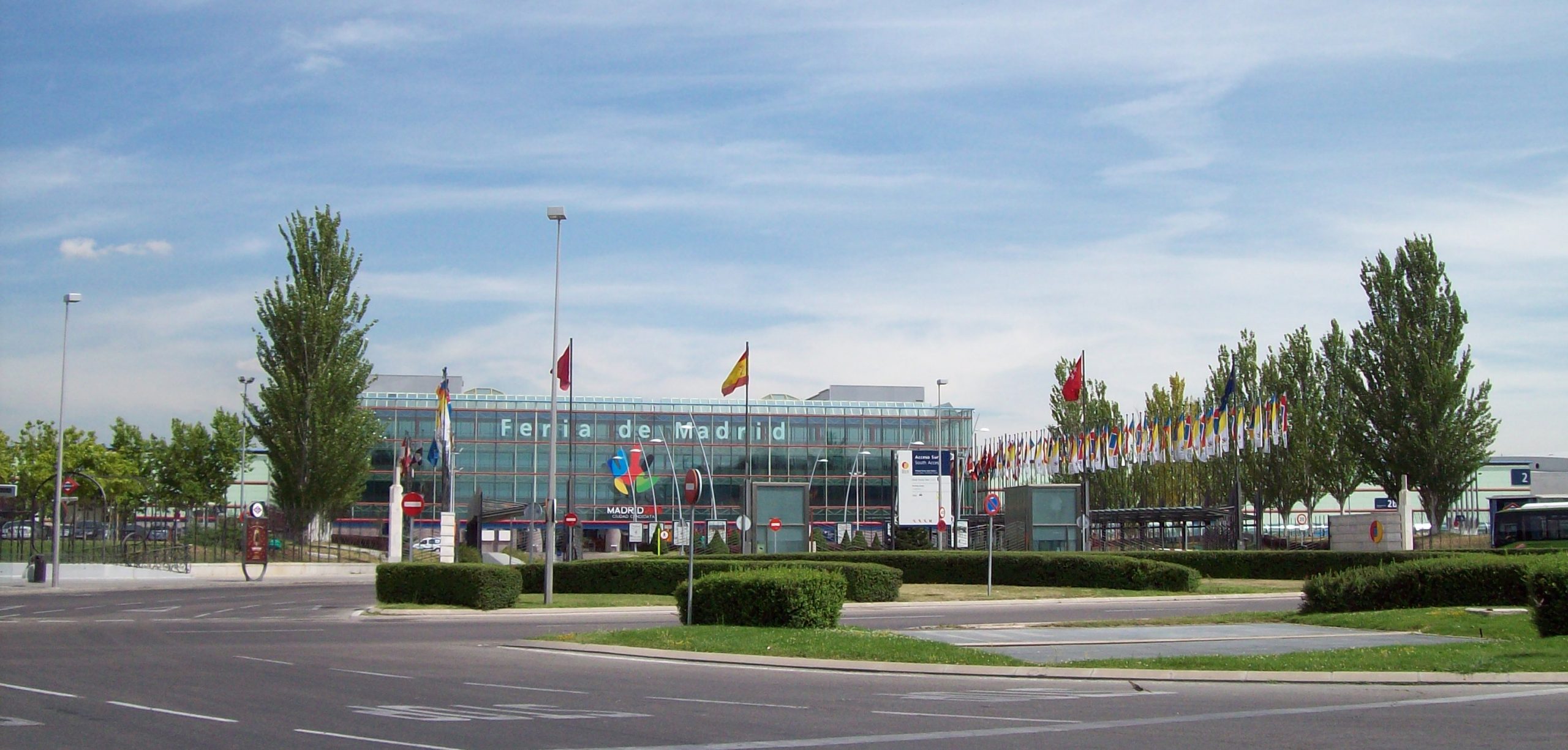 Entrada del Palacio Municipal IFEMA, árboles a los lados bandera de España en el centro. Autor Luis García
